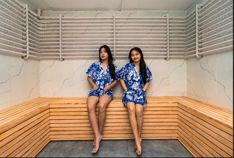 사우나 벤치에 앉아 있는 똑같은 파란색 파자마를 입은 두 여성